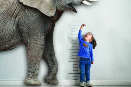 Afrikaausstellung Kind vergleicht ihre Größe mit einem Elefanten