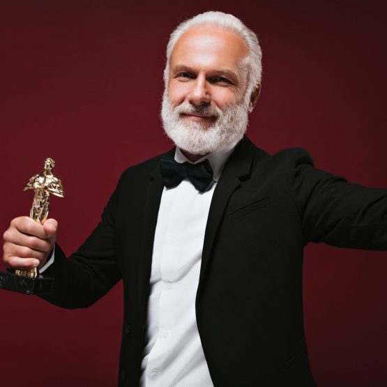 Attractive man in suit takes selfie with oscar statuette positive guy with grey beard in black clo